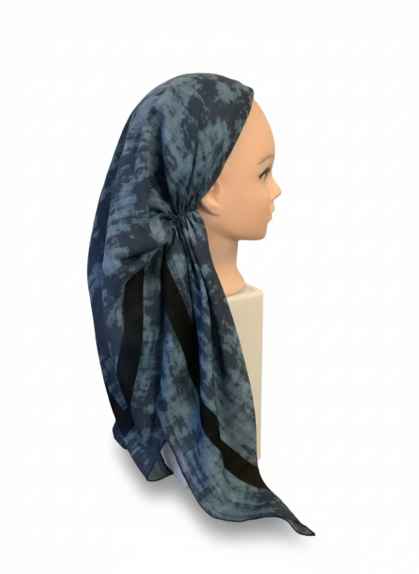 Mannequin head wearing a blue patterned tichel headscarf on a white background