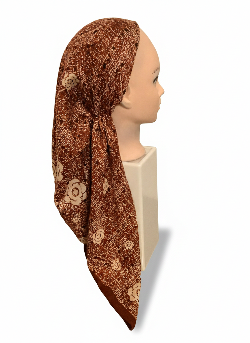 Mannequin head wearing a brown patterned headscarf on a white background