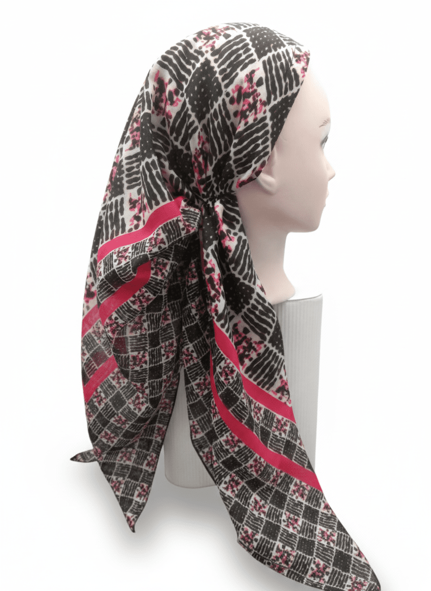 Mannequin head wearing a patterned scarf with red and black design on a white background