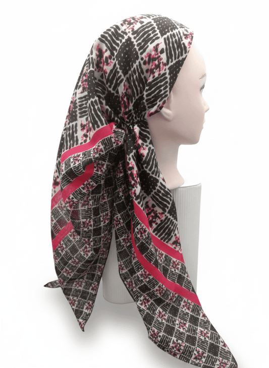 Mannequin head wearing a patterned scarf with red and black design on a white background