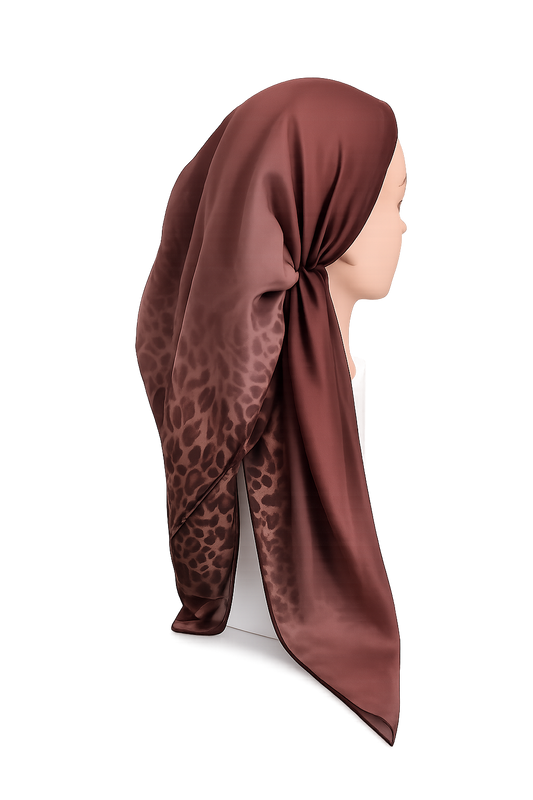 A red tichel with a leopard print pattern, styled on a mannequin head against a white background.