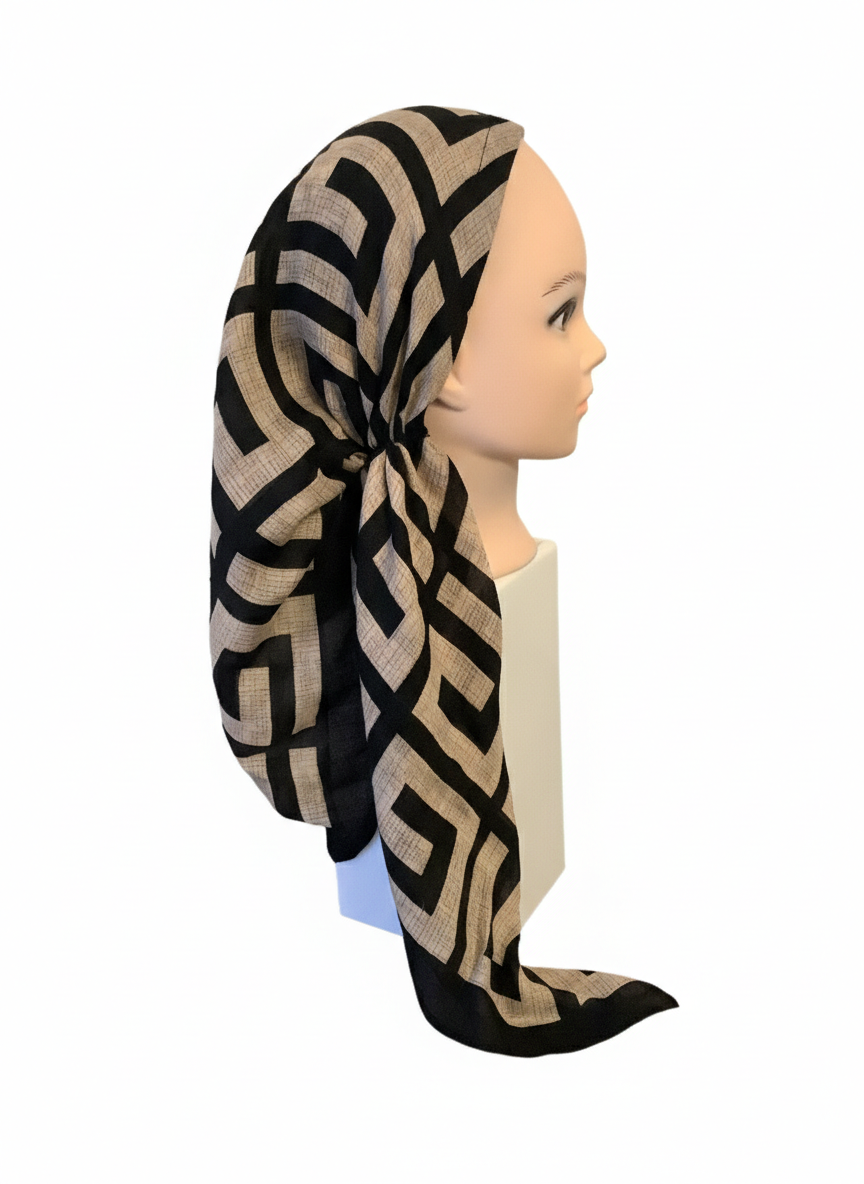 Mannequin head wearing a black and beige patterned headscarf on a white background