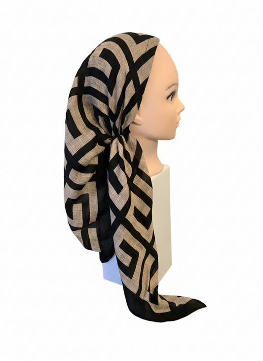 Mannequin head wearing a black and beige patterned headscarf on a white background