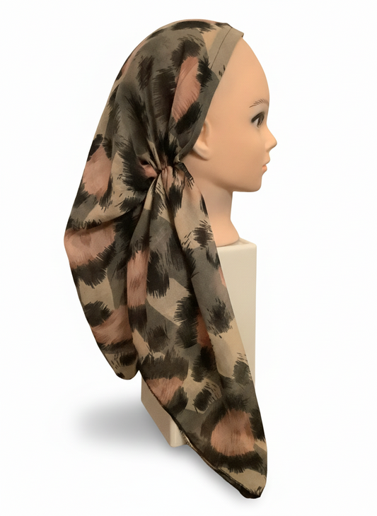 Mannequin head wearing a patterned tichel scarf on a white background