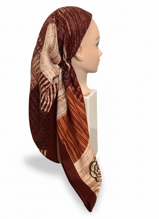 Mannequin head wearing a patterned headscarf on a white background