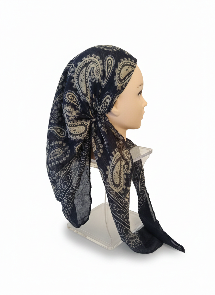 Mannequin head wearing a black and gold patterned headscarf on a white background