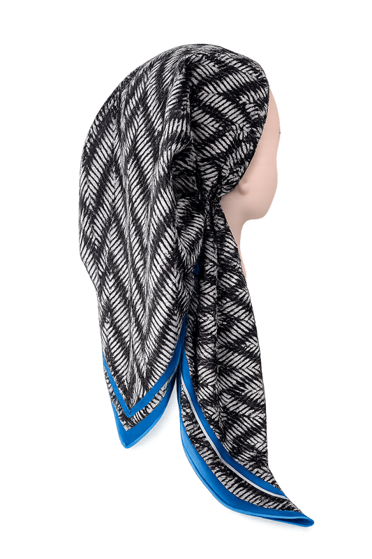 A black and white patterned scarf with a bright blue border, draped on a mannequin head against a plain white background.
