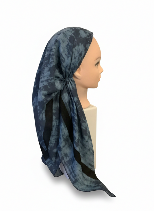 Mannequin head wearing a blue patterned tichel headscarf on a white background