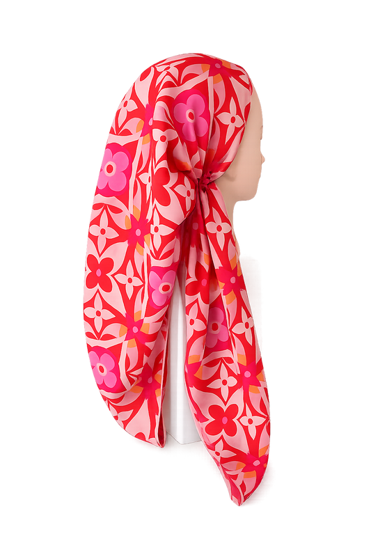 Mannequin head wearing a red floral patterned pretied tichel on a white background