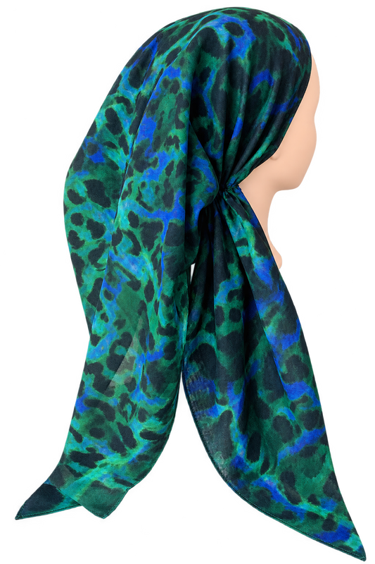 A sheer scarf with a green, blue, and black leopard print, styled on a mannequin head against a plain white background.