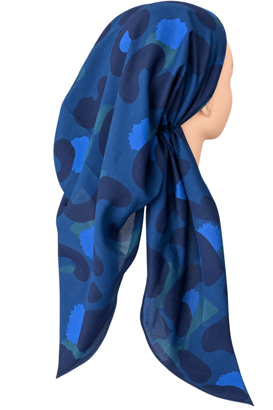 A blue patterned headscarf draped on a mannequin head, shown from the side against a plain white background.