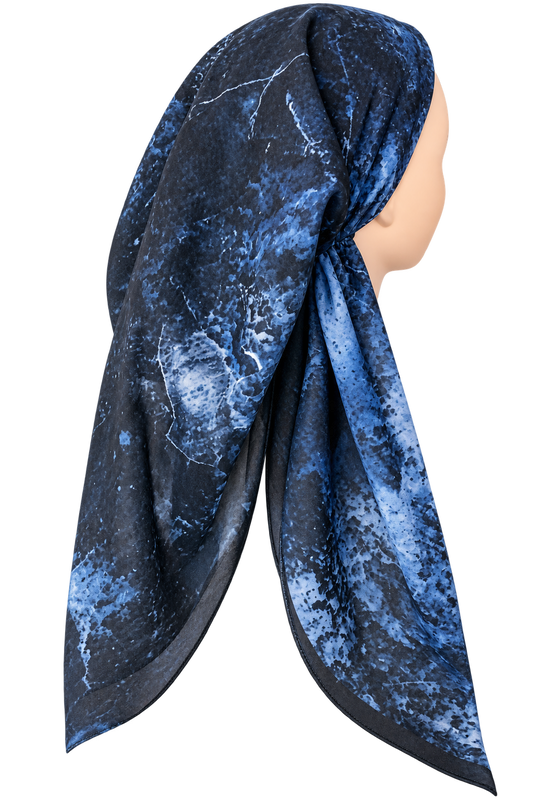 A blue and black abstract marble-patterned tichel wrapped on a mannequin head, shown against a plain white background.