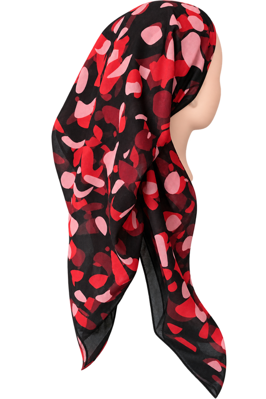 A sheer black headscarf with a red and pink abstract petal-like pattern, draped on a mannequin head against a plain white background.