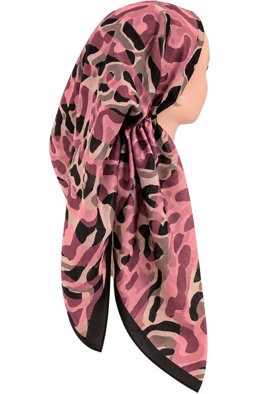 A pink and black camouflage-patterned pretied tichel scarf styled on a mannequin head, shown from a side profile against a solid white background.