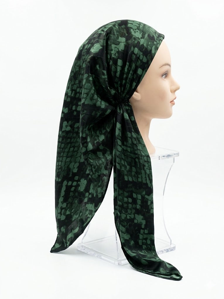 Green patterned headscarf on a mannequin head against a white background