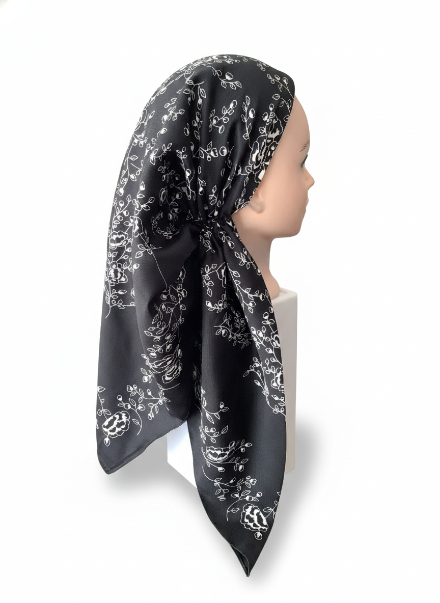 Pretied tichel with white floral patterns on a mannequin head against a white background