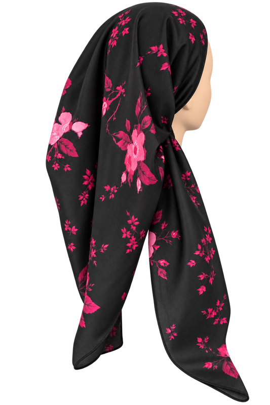 A black tichel with a vibrant pink floral pattern, draped on a mannequin head against a plain white background.