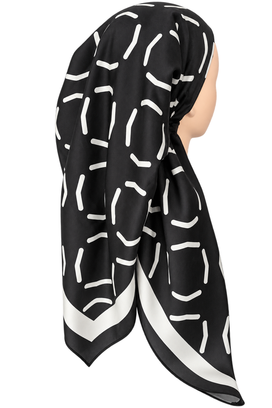 A black silk-like tichel with a white abstract line pattern and a white border, displayed on a mannequin head against a plain white background.