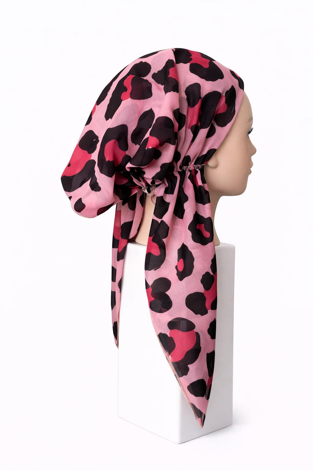Mannequin head wearing a pink leopard print headscarf on a white background